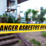 Yellow caution tape reading "Danger Asbestos Dust" strung outside a home.