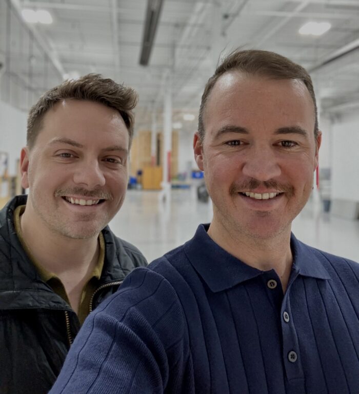 A selfie of two brown-haired men with moustaches.